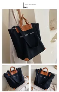 Detail of black canvas tote bag showing brown leather handles and color contrast design