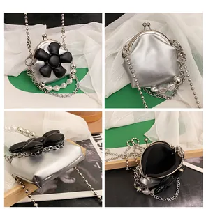 Detailed view of mini silver kiss-lock bag with black 3D flower and pearl chain strap