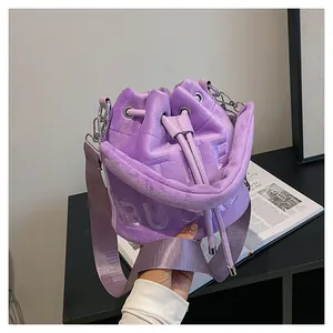Detail of purple plush bucket bag with The Bucket lettering and fabric shoulder strap
