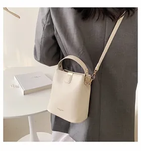 Detail of cream bucket bag with gold metal buckle and Fashion & Bags logo on soft leather