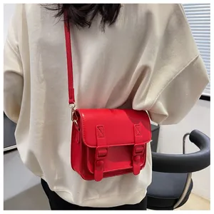 Detail van een stijlvolle rode crossbodytas gedragen bij een witte oversized trui