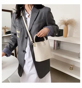Chic cream mini bucket bag shown on model with adjustable strap and gold hardware