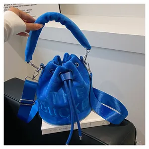 Detail of blue velvet bucket bag with embossed lettering and plush top handle