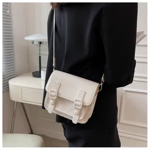 Detail van crème lederen crossbody tas met klepsluiting en parallelle riemaccenten