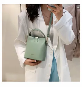 Detail view of a mint green bucket bag featuring premium leather texture and metallic logo