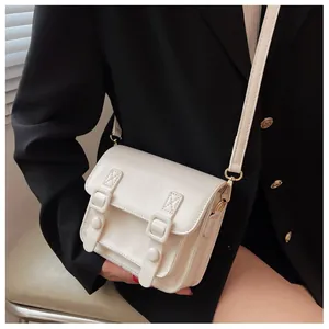 Witte minimalistische PU-lederen crossbodytas gedragen op een zwarte blazer voor contrast