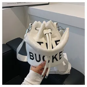 Detailed view of white plush bucket bag featuring black THE BUCKET text and drawstring