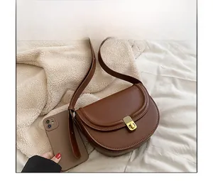 Brown PU leather saddle bag detail with gold metal lock and phone for size reference