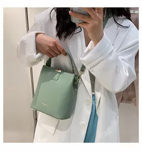 Mirror selfie showing a light green matte leather bucket bag with a top handle and gold logo