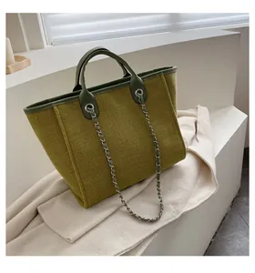 Detalle del bolso tote de tweed verde oscuro con asa de cuero y correa de cadena