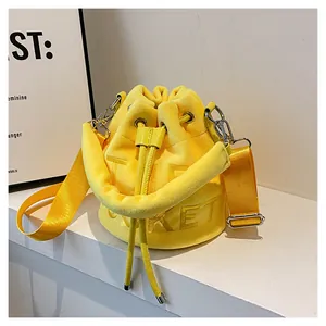 Detail view of yellow plush bucket bag with TICKET textured embossing and drawstring close