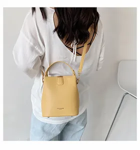 Detailed view of yellow leather bucket bag with adjustable strap worn by a model