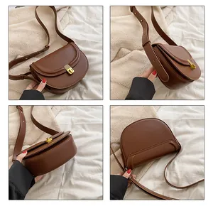 Detail view of a brown faux leather saddle bag with gold metal clasp and adjustable strap