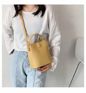 Detailed view of the yellow leather bucket bag with top handle and golden hardware