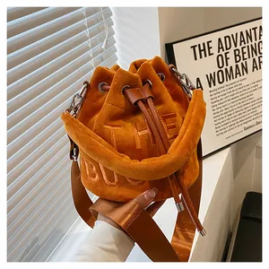 Detail of orange plush bucket bag with The Bucket embroidery and wide strap