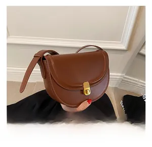 Detailed view of dark brown saddle bag with golden metal buckle and smooth leather texture