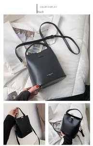 Detail view of black leather bucket bag with gold hardware and protective base studs