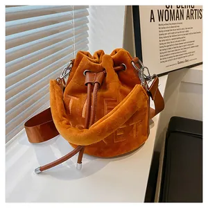 Detail of orange velvet bucket bag featuring THE TICKET embossed text and drawstring