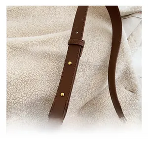 Close-up of adjustable brown leather strap with gold buckle on a stylish saddle bag