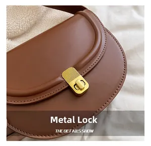 Close-up of golden hardware clasp on brown PU saddle bag with cozy fleece lining detail