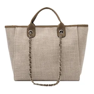 Bolso tote de lona beige con ribete de cuero marrón y detalle de cadena de metal