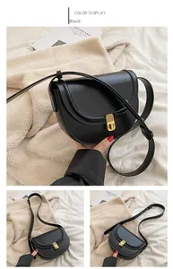 Detail view of black PU leather saddle bag with gold buckle and adjustable strap