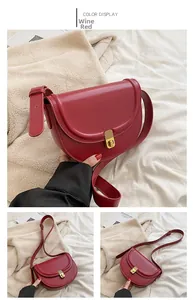 Detailed view of wine red saddle bag with adjustable strap and golden metal rotary lock