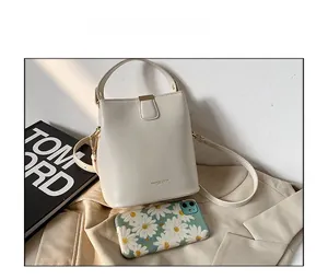 Size comparison of the cream bucket bag next to a smartphone and a fashion book