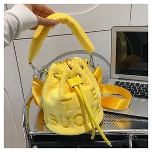 Close-up of bright yellow plush drawstring bucket bag with the bucket embroidery