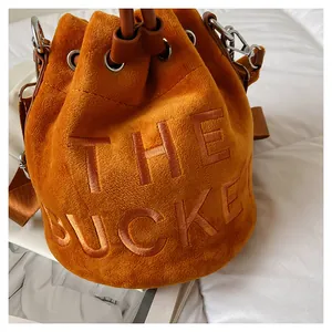 Detail of caramel velvet bucket bag featuring premium embroidered The Bucket text texture