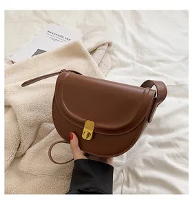 Close-up of a brown PU leather saddle bag with a vintage gold clasp and strap