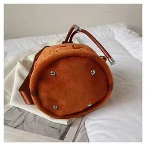 Detailed bottom view of orange plush bucket bag with metal studs and Lucky embossing