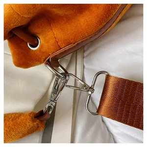Detail of plush orange bucket bag featuring brown leather trim and silver metal hardware