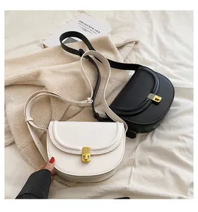 Detail of elegant PU leather saddle bags in black and white with gold rotating locks