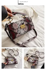 Close-up of snake skin print texture with golden metal buckle on the stylish white handbag