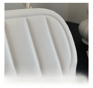 Vue macro de la texture matelassée verticale sur un sac à main élégant en cuir blanc et doré