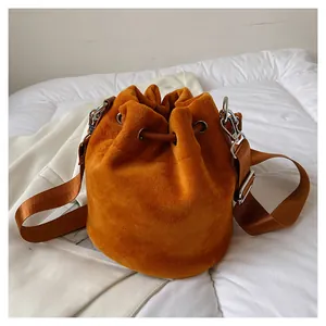 Detail of ginger velvet bucket bag with drawstring closure and wide nylon strap