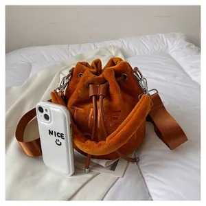 Detail of caramel velvet bucket bag with brown leather drawstring and wide fabric strap