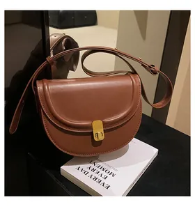 Detail of a brown PU leather saddle bag featuring a vintage gold rectangular metal clasp