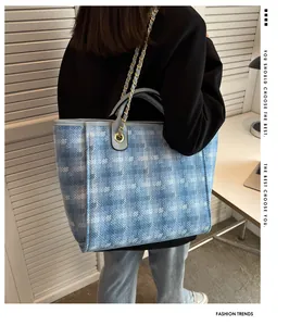 Blue and white geometric pattern tote bag with chain strap shown on model's shoulder