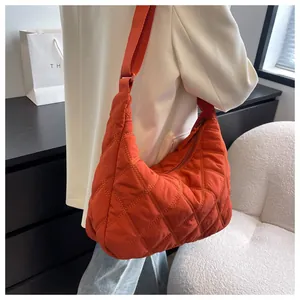 Detail einer orangefarbenen Stepptasche aus Nylon mit verstellbarem Riemen und Verschluss