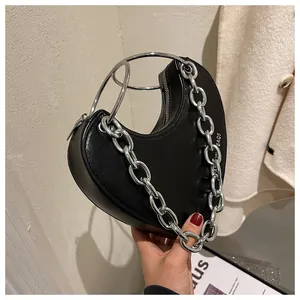 Detail of black heart-shaped handbag with silver metal ring handles and thick chain strap