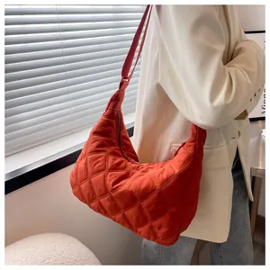 Detail einer orangefarbenen Stepptasche mit Halbmondform und verstellbarem Gurt