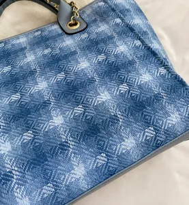 Detail of blue woven tote bag showing geometric texture and gold chain strap