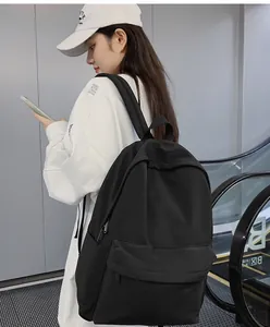 Black minimalist backpack shown from side angle in a shopping mall setting
