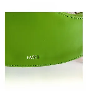 Detail of bright green faux leather bag with stitching and silver logo text