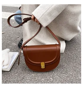Detail of vintage dark brown saddle bag with gold metal clasp and smooth leather texture