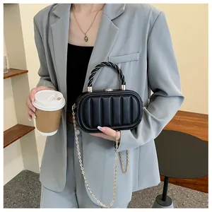 Détail du sac boîte plissé noir avec poignée en corde et chaîne dorée sur mannequin