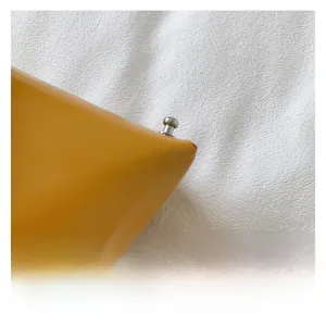 Macro detail of yellow textured leather bag with polished silver metal hardware stud