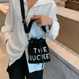 Fashionable black plush bucket bag with The Bucket lettering and wide shoulder strap